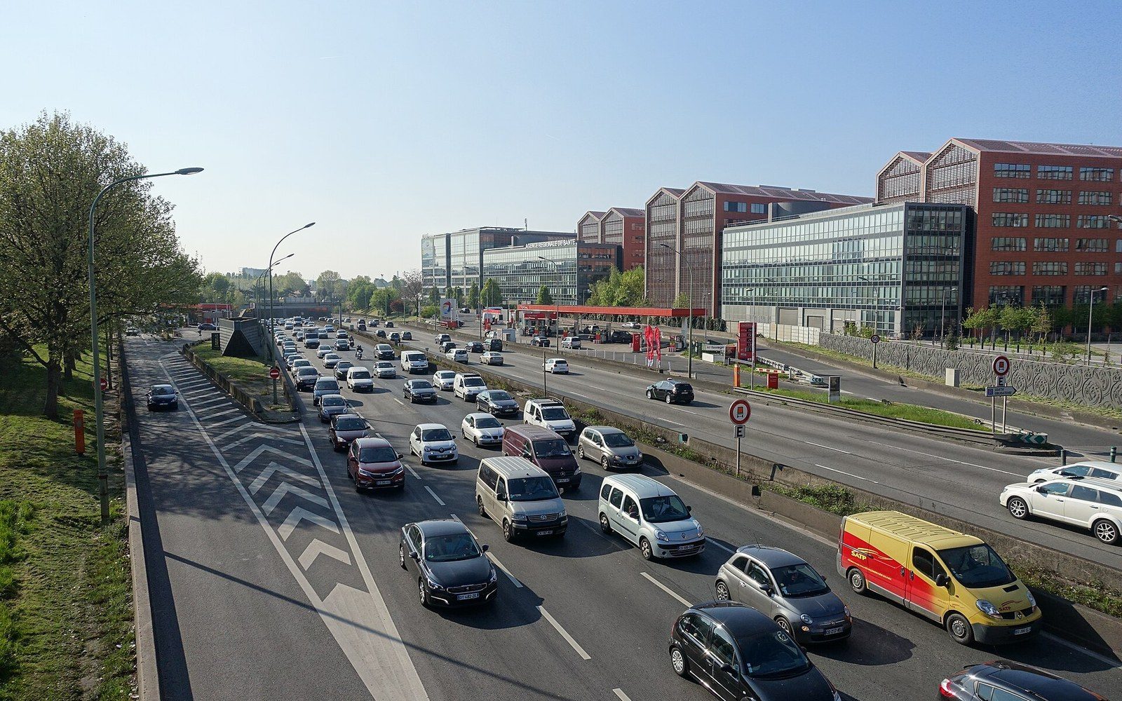 A multi-lane ring road at dusk with apartment blocks beyond